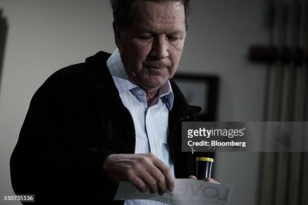 John Kasich, governor of Ohio and 2016 Republican presidential candidate, looks at a bumper sticker reading "Love>Hate" during a town hall event at...