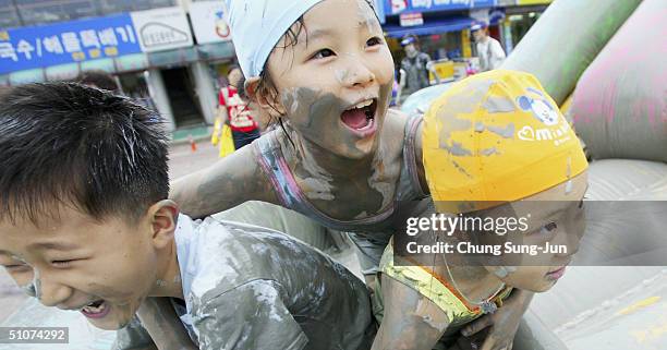 Young participants enjoy the mud on the West Coast beach during the Boryeong Mud Festival on July 16, 2004 in Daecheon, South Korea. This is the...