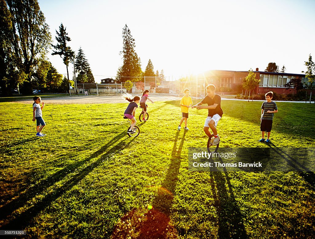 Group of kids riding unicycles and playing