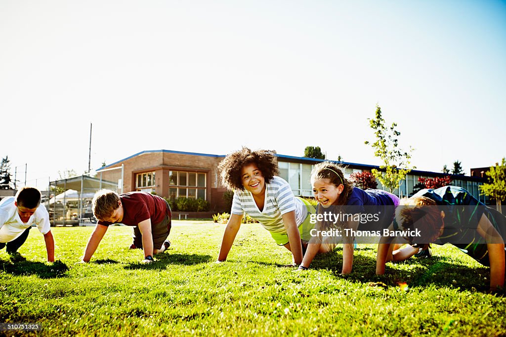 Two laughing girls doing push ups during class