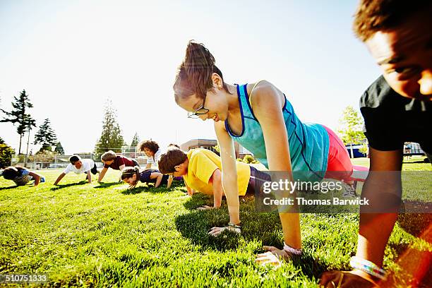 young girl doing push ups with friends - only kids at sky stock pictures, royalty-free photos & images