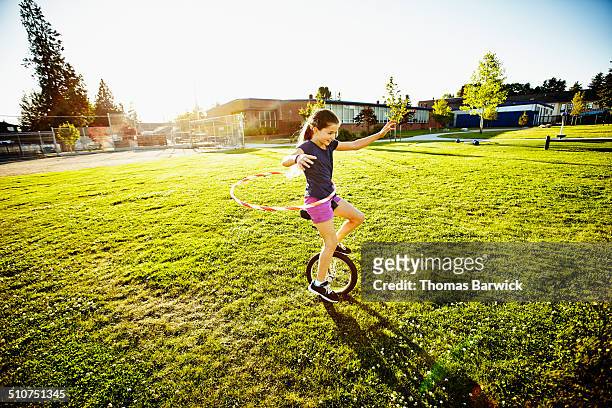 young girl hula hooping while riding unicycle - unicycle stock pictures, royalty-free photos & images