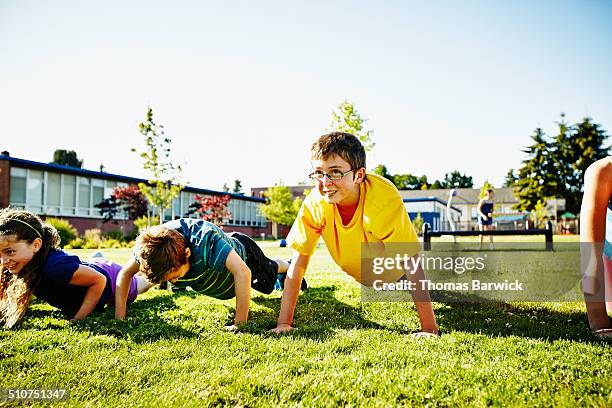 young boy doing push ups with friends during class - sport community center stock pictures, royalty-free photos & images