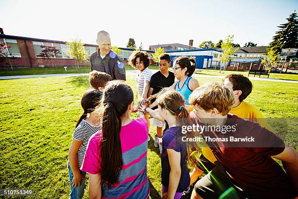 Group of kids in huddle with coach on field