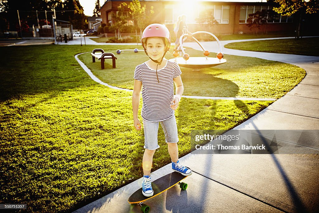 Young girl riding skateboard on cement pathway