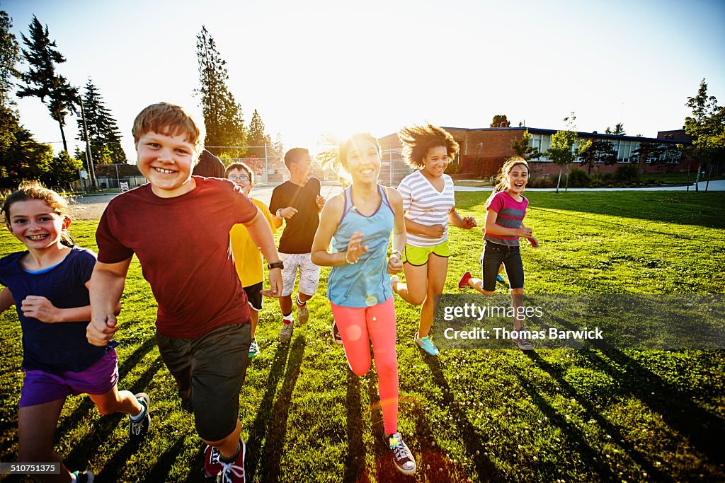 Group of smiling boys and girls running on field