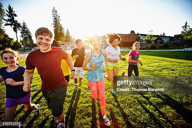 group of smiling boys and girls running on field - 13 year old stock pictures, royalty-free photos & images