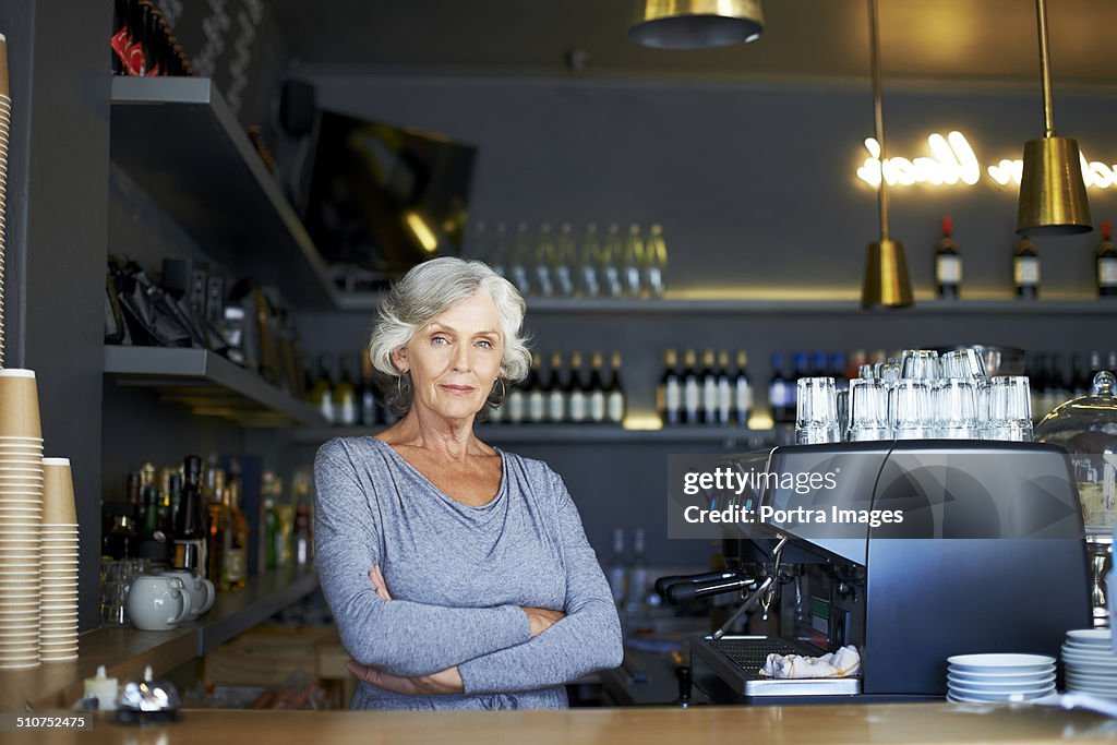 Confident senior woman standing at cafe counter