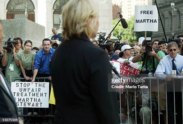 Martha Stewart supporters look on as she speaks to the media outside Federal Court after her sentencing hearing July 16, 2004 in New York City....