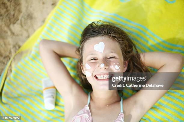 a girl with sunscreen on the face on the beach - girls sunbathing stock pictures, royalty-free photos & images