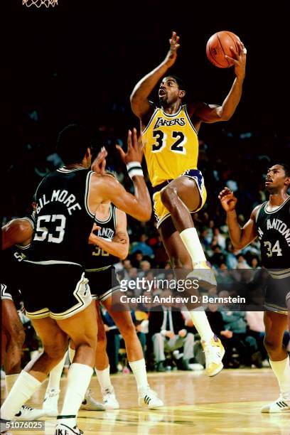 Earvin 'Magic' Johnson of the Los Angeles Lakers takes the ball to the basket against Artis Gilmore of the San Antonio Spurs circa 1985 at The Great...