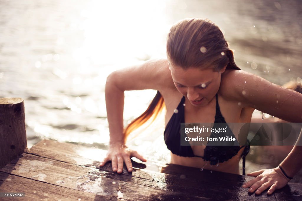 Young woman pushing herself up as she exits a lake