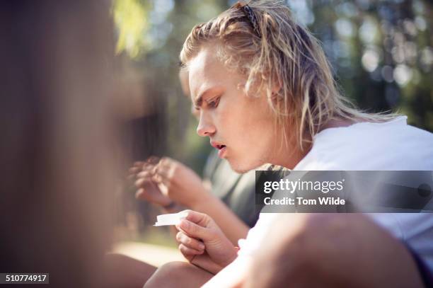 young man holding a paper for rolling cigarettes - last day bildbanksfoton och bilder