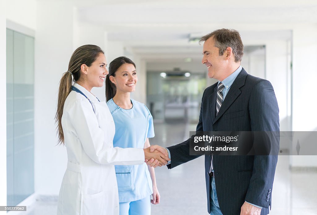 Doctor greeting health insurance agent with a handshake