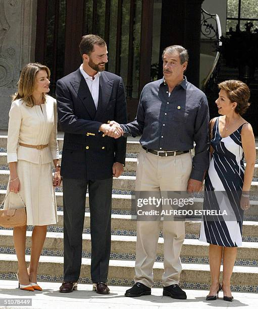 Prince Felipe de Borbon shakes hands with Mexican President Vicente Fox while wives Letizia Ortiz and Martha Sahagun look on 17 July 2004, at Los...