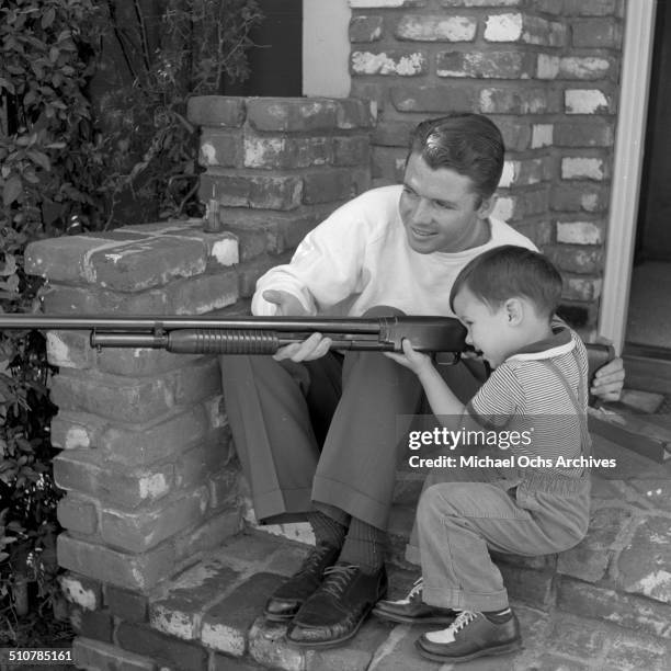 Audie Murphy show his young son Terry how to hold a rifle in Perris,CA.
