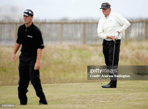 Colin Montgomerie of Scotland plays his approach shot to the 1st green as Mike Weir of Canada looks on during the final round of the 133rd Open...