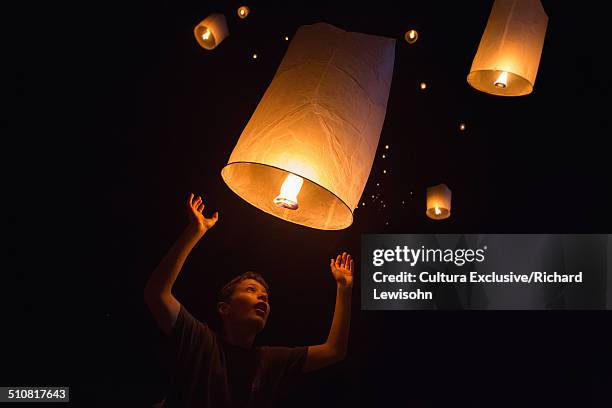 portrait of boy releasing chinese lanterns on new year's eve, krabi, thailand, southeast asia - floating lanterns stock-fotos und bilder