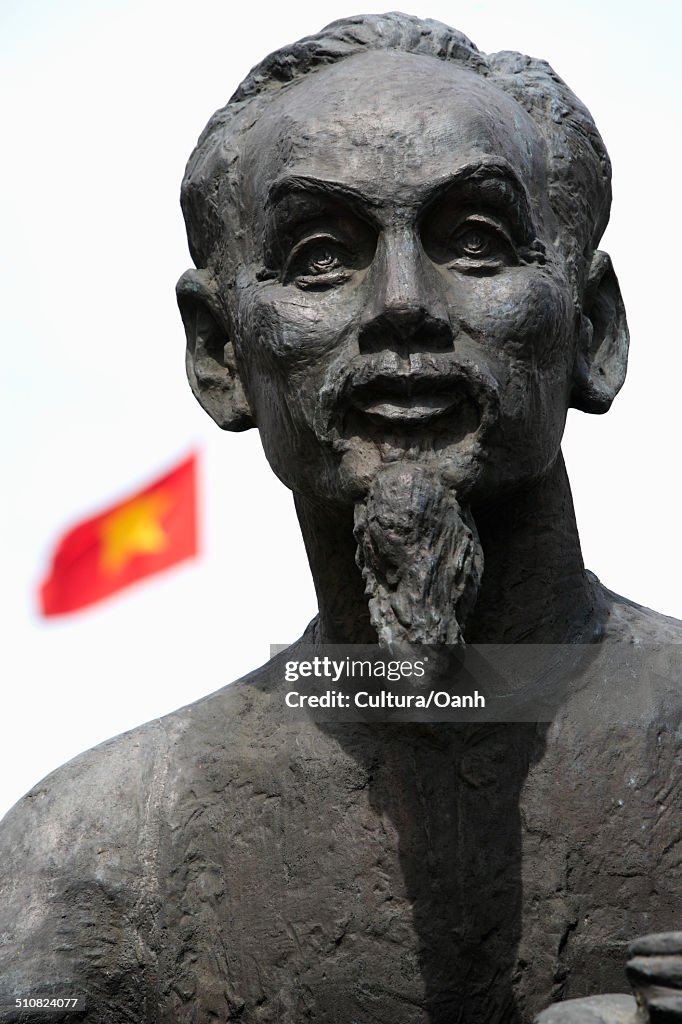 Statue of Ho Chi Minh with Vietnamese flag in background