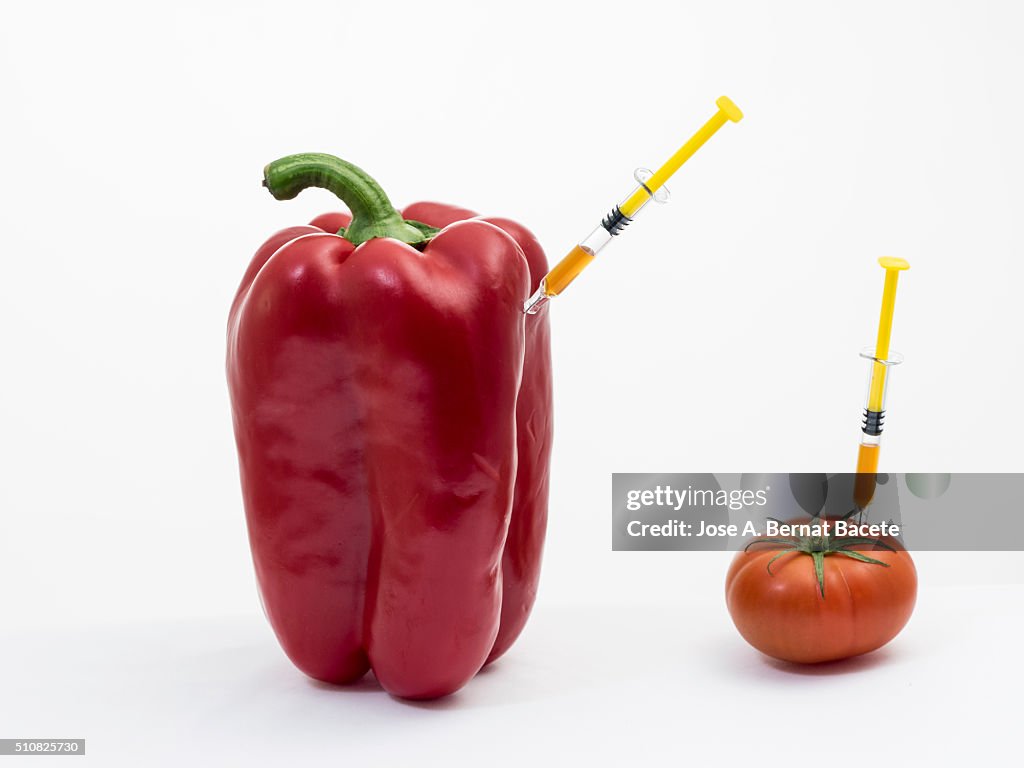 Pepper and tomato with a syringe stuck concept of transgenic foods