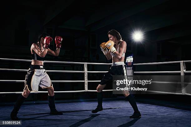 female boxers fighting in a boxing ring - duelleren stockfoto's en -beelden