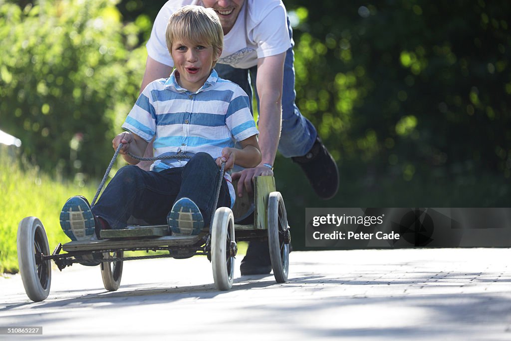 Boy being pushed by father in go kart