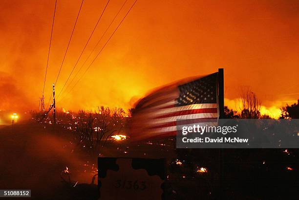An American flags flies near downed power lines and burning brush at the Crown Fire on July 20, 2004 near Acton, California The fire is threatening...
