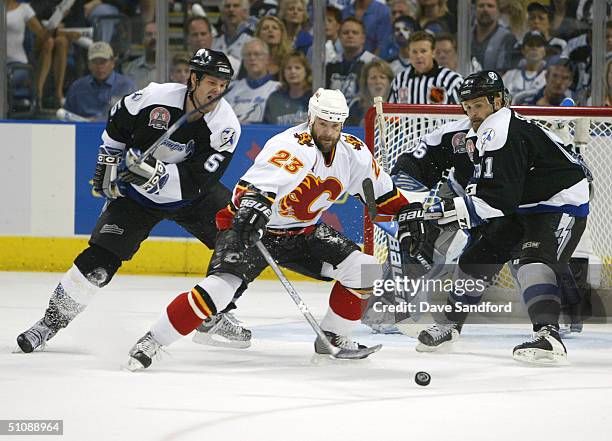 Martin Gelinas of the Calgary Flames skates for the puck against Jassen Cullimore and Cory Stillman of the Tampa Bay Lightning in Game seven of the...