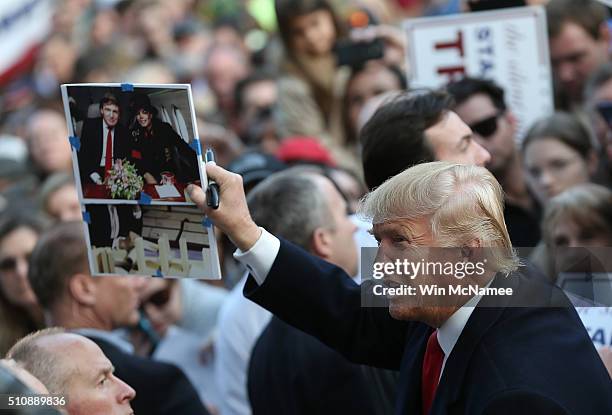 Republican presidential candidate Donald Trump holds up a photo of himself with pop star Michael Jackson that a member of the audience asked him to...