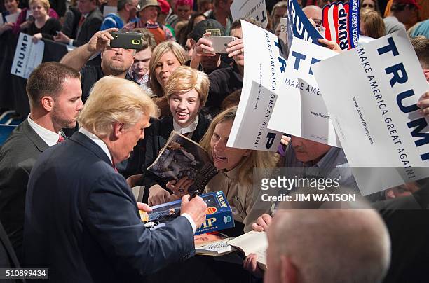 Republican presidential candidate Donald Trump signs a Trump doll for a girl dressed in costume like him during a campaign rally in Sumter, South...