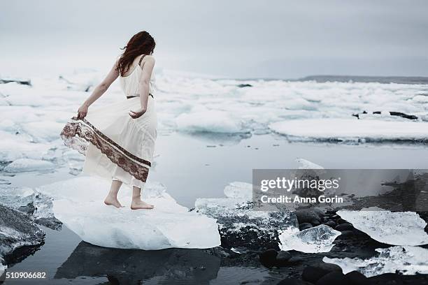 young woman in vintage sheer white nightgown standing barefoot on iceberg at jokulsarlon glacial lagoon, iceland, back view - see through negligee stock pictures, royalty-free photos & images