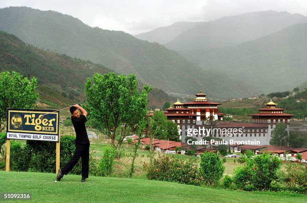 Golfer Takes A Swing At The Royal Thimpu Golf Course May 20, 2000 In Thimpu, Bhutan. The Trashichhoe Dzong In The Back Ground Is A Backdrop For...