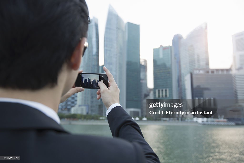 Rear view of man taking photos of cityscape.