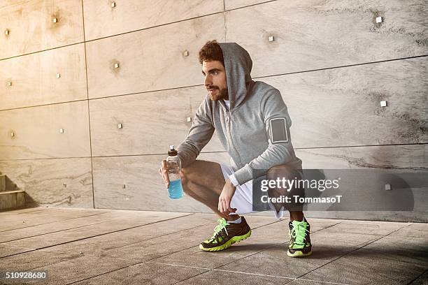 athlete crouched with a sport drink - mens track stock pictures, royalty-free photos & images