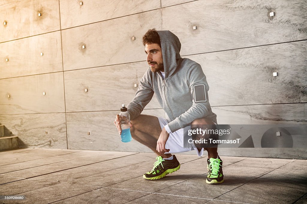 Athlete crouched with a sport drink