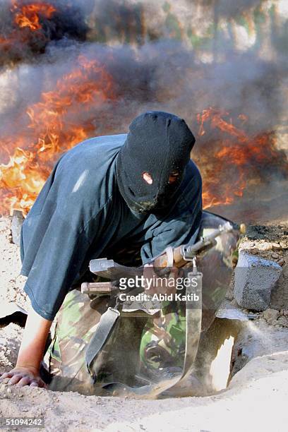 Palestinian Militant Youth Trains How To Use A Weapon As A Fire Burns Behind Him May 11, 2002 In Rafah Refugee Camp, Located In The Gaza Strip....