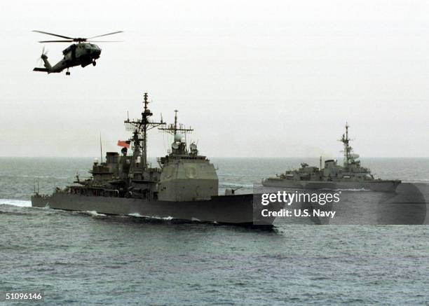 As Thick Gray Clouds Hang Overhead The Air An Hs-60 Seahawk Flies Around The USS Anzio As The U.S. French Mountcalm Sails Into Position For The...