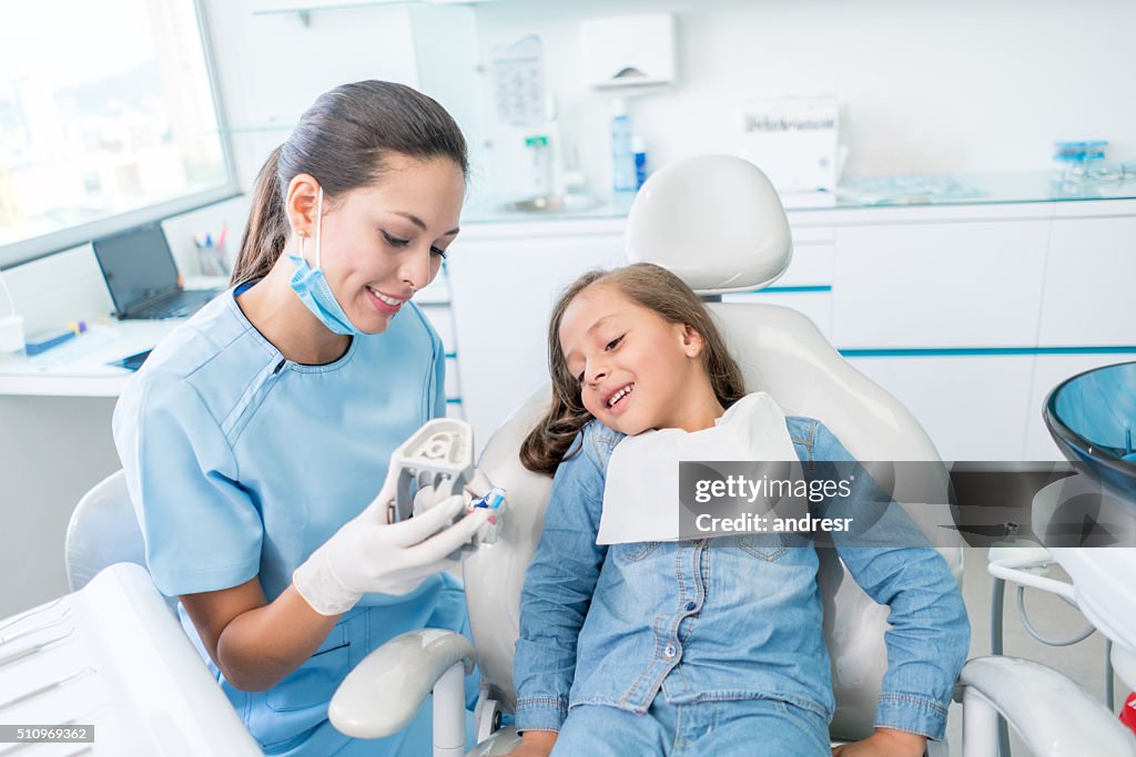 Mädchen beim Zahnarzt lernen, wie man ihre Zähne putzt