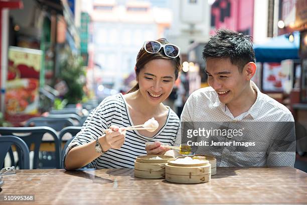 asian man and woman eating dumplings. - dim sum stockfoto's en -beelden