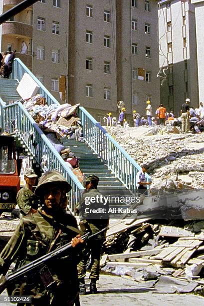 Salvaged Personal Belongings Are Piled On The Stairs Of An Overpass While Soldiers Keep The Curious Away As Rescue Workers Look For Survivors Under...