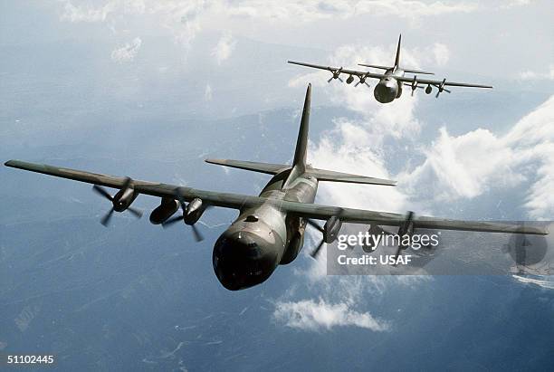 Two C-130E Hercules Aircraft Flying Over Mountainous Terrain.