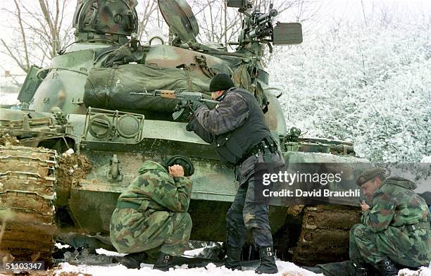Yugoslav Special Forces Policeman Shoots His Rifle At Opposing Kosovo Liberation Army Forces As A Yugoslav Army Tank Driver Covers His Ears After...