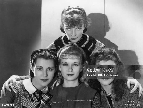 American actress Katharine Hepburn stands behind costars Frances Dee , Joan Bennett , and Jean Parker as they pose for a publicity portrait to...