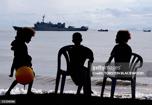 This files dated 24 July 2003 shows Melanesian children watching the Australian-led intervention force based on the HMAS Manoora preparing to come...