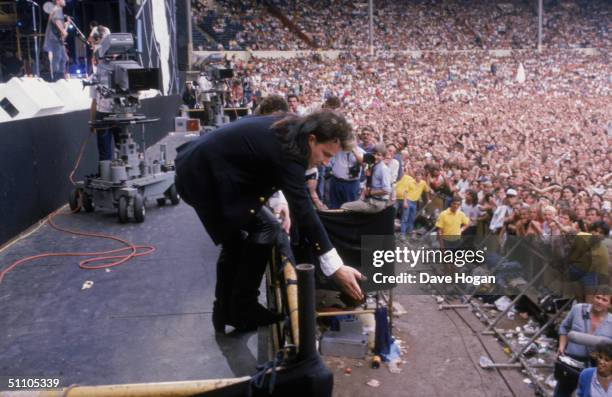 Irish singer Bono reaches down to an audience member during U2's performance at the Live Aid charity concert, Wembley Stadium, London, 13th July 1985.