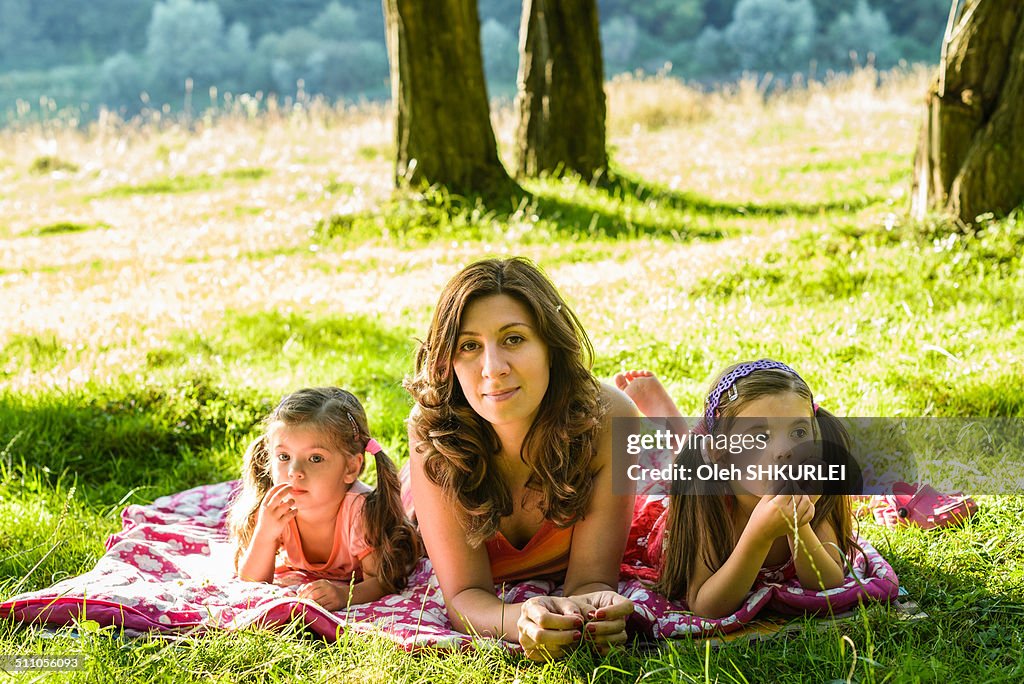 Portrait of mother with daughters lying in shadow