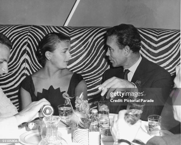 Dominican diplomat and socialite Porfirio Rubirosa smokes cigarettes with Mrs. Messmore Kendall at the El Morocoo restaurant, New York, New York,...