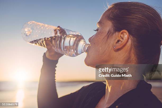 woman drinking water seaside. - water photos et images de collection