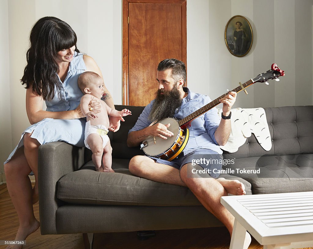 Father playing music to baby and wife at home