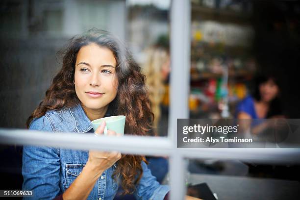 woman looking out of a cafe window - cafe window stock pictures, royalty-free photos & images